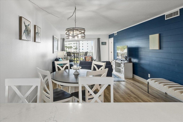 dining room featuring hardwood / wood-style floors, an inviting chandelier, and wood walls