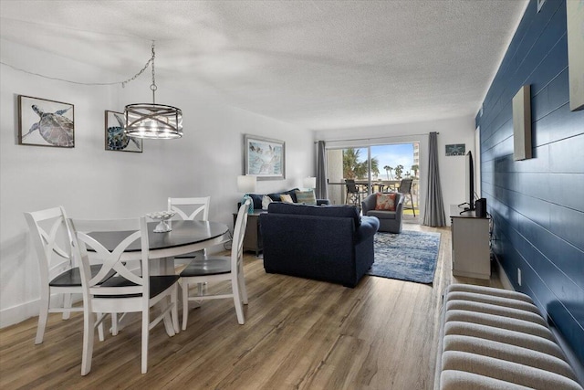 dining area with hardwood / wood-style floors, a chandelier, and a textured ceiling