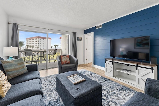909 Santa Rosa Blvd Unit 138, Fort Walton Beach, FL 32548 - living room featuring light hardwood / wood-style floors, a textured ceiling, and wooden walls