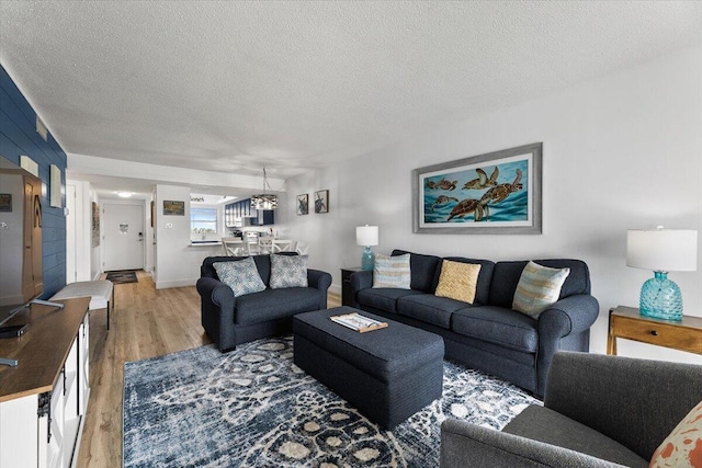 living room featuring an inviting chandelier, hardwood / wood-style floors, and a textured ceiling