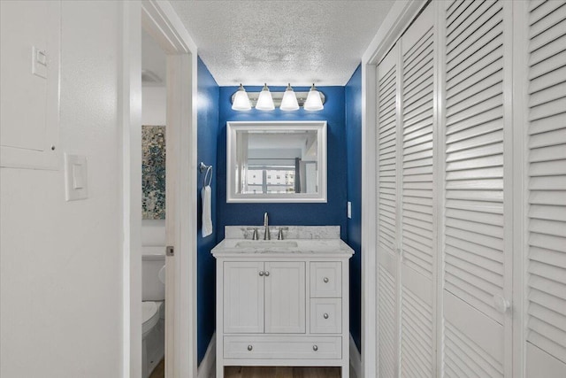 bathroom featuring vanity, a textured ceiling, and toilet