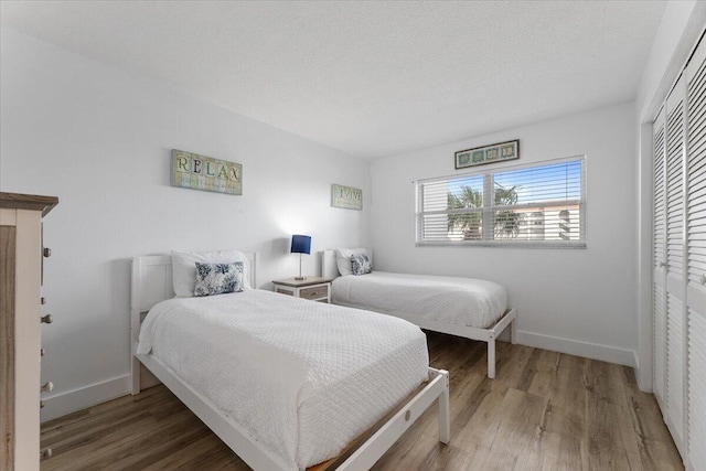 bedroom featuring a closet, wood-type flooring, and a textured ceiling