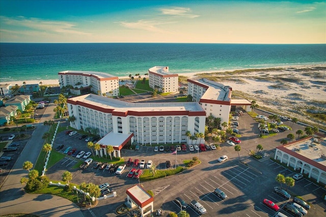 aerial view at dusk with a water view and a view of the beach