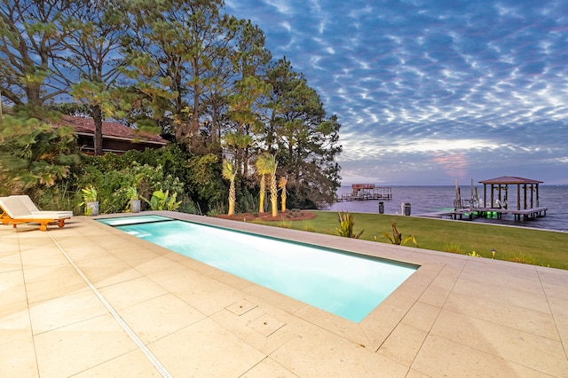 view of swimming pool featuring a patio area, a water view, and a yard