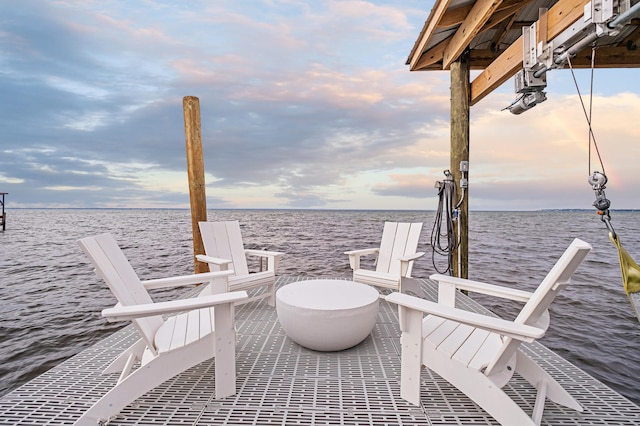 patio terrace at dusk featuring a boat dock and a water view