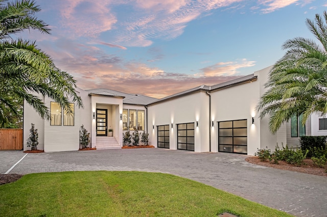 view of front of property featuring a lawn, french doors, and a garage