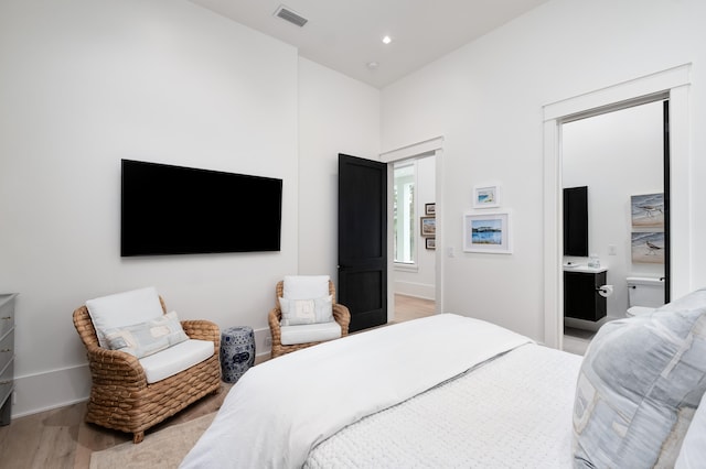 bedroom featuring ensuite bathroom and light wood-type flooring