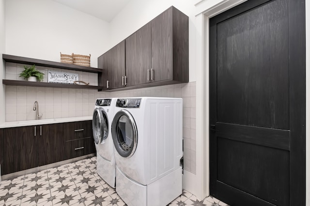 clothes washing area featuring washer and clothes dryer, sink, and cabinets