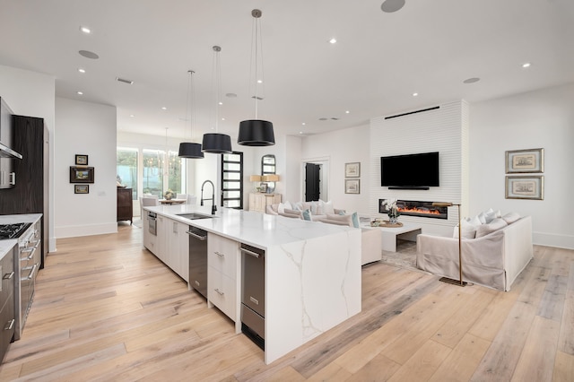 kitchen featuring hanging light fixtures, white cabinets, a spacious island, and light wood-type flooring