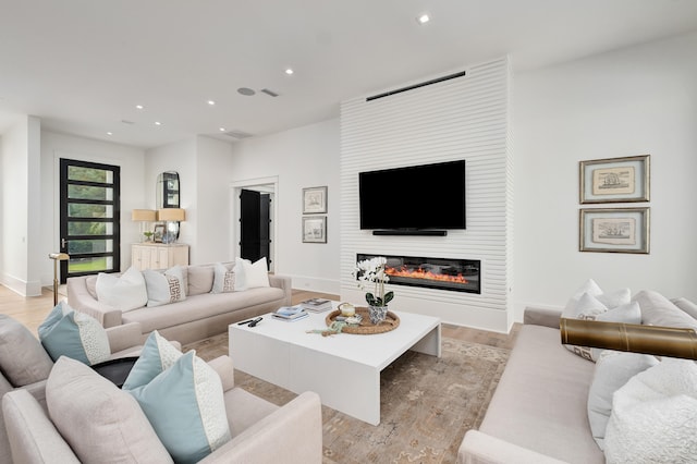 living room with a large fireplace and light hardwood / wood-style floors