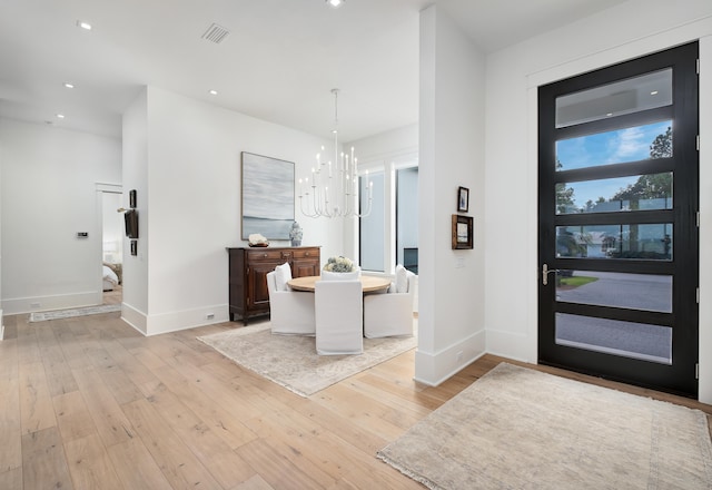 foyer with an inviting chandelier and light wood-type flooring