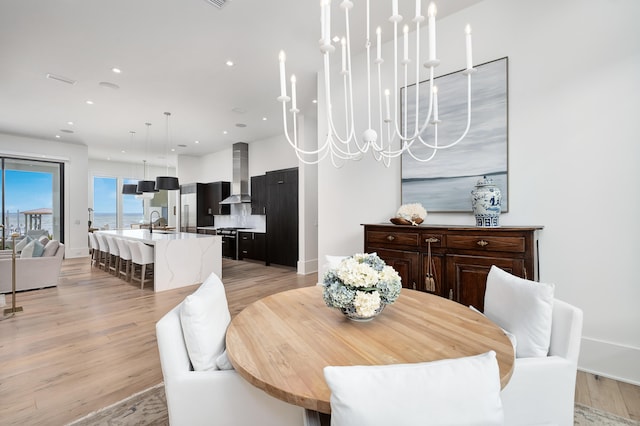 dining area with light hardwood / wood-style flooring, a notable chandelier, and sink