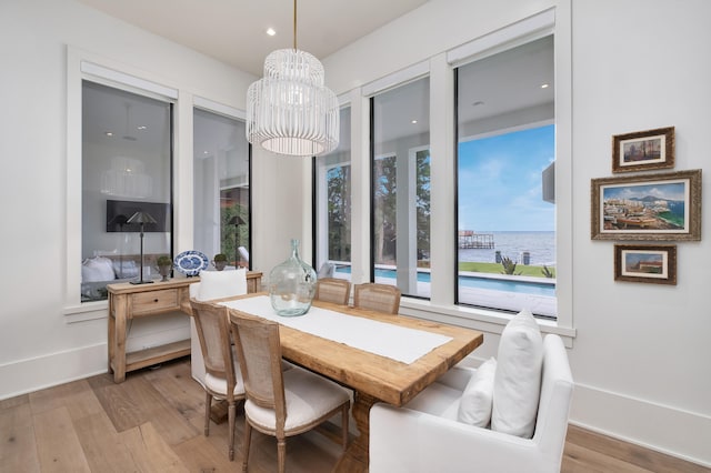 dining area with hardwood / wood-style flooring, a water view, and a chandelier