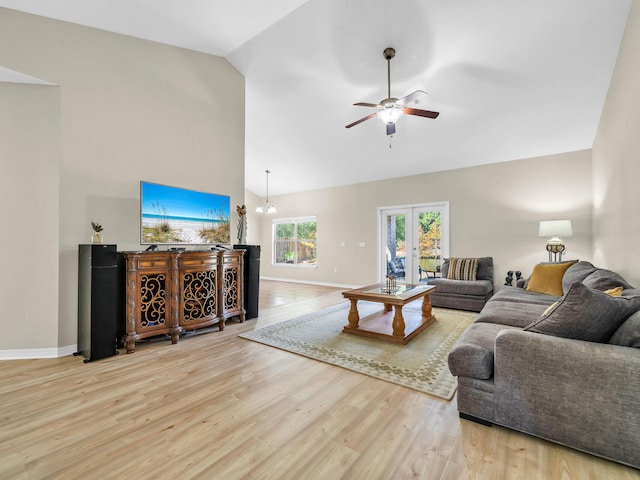 living room featuring ceiling fan with notable chandelier, light wood-type flooring, and high vaulted ceiling