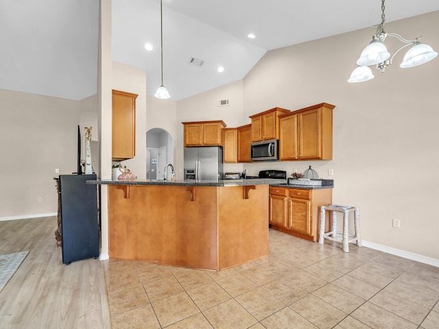 kitchen with a kitchen bar, stainless steel appliances, sink, pendant lighting, and a notable chandelier