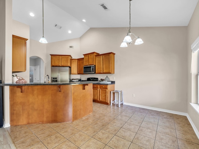 kitchen featuring a kitchen bar, appliances with stainless steel finishes, light tile patterned floors, an inviting chandelier, and hanging light fixtures