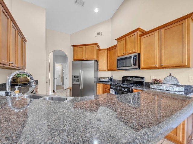 kitchen featuring sink, stainless steel appliances, high vaulted ceiling, kitchen peninsula, and dark stone countertops