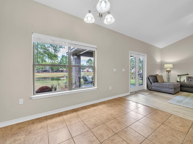 unfurnished living room with french doors, light tile patterned floors, and an inviting chandelier