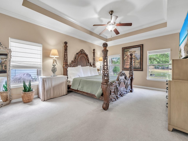 bedroom featuring a raised ceiling, multiple windows, ceiling fan, and light colored carpet