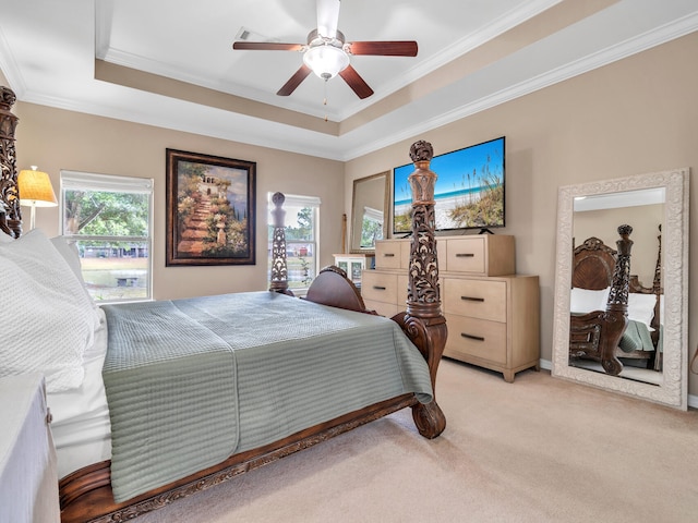 bedroom featuring ceiling fan, light colored carpet, crown molding, and a tray ceiling