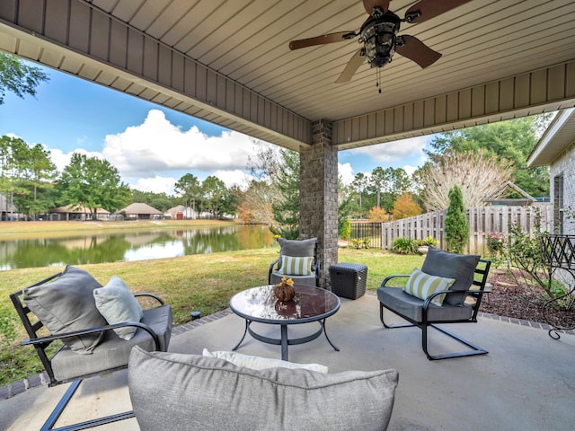 view of patio / terrace featuring ceiling fan, a water view, and an outdoor living space