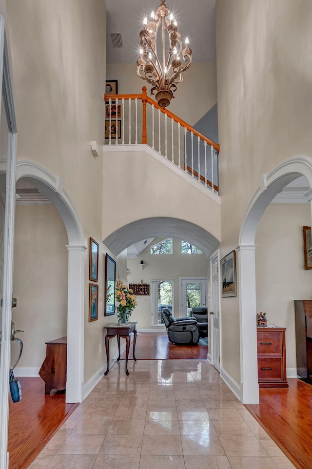 entryway featuring light hardwood / wood-style flooring, ornamental molding, and a high ceiling