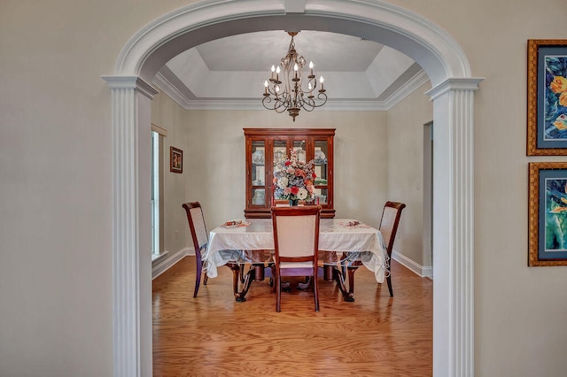 dining area featuring an inviting chandelier, light hardwood / wood-style flooring, crown molding, and a raised ceiling