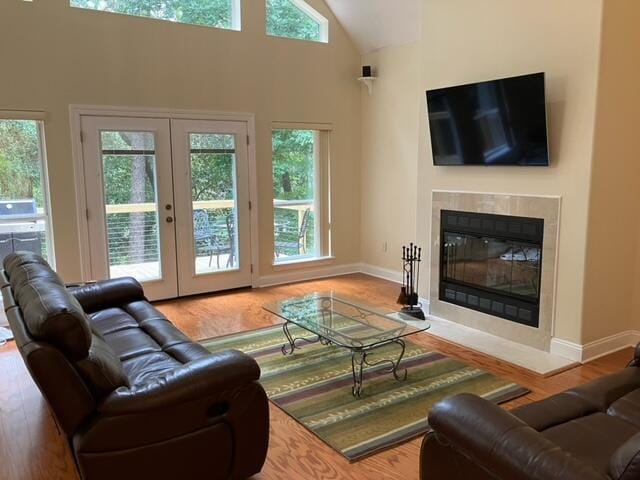 living room with high vaulted ceiling, wood-type flooring, and a healthy amount of sunlight