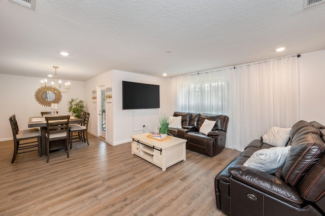 living room featuring a textured ceiling, a notable chandelier, and light hardwood / wood-style floors