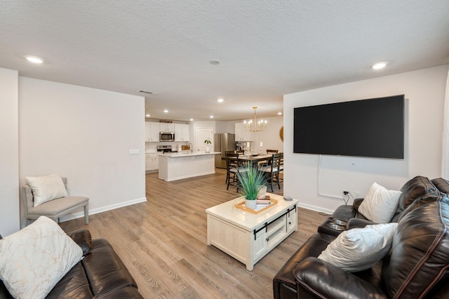 living room featuring light hardwood / wood-style flooring, a notable chandelier, and a textured ceiling