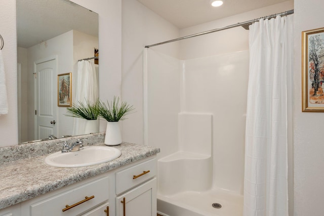 bathroom featuring walk in shower and vanity