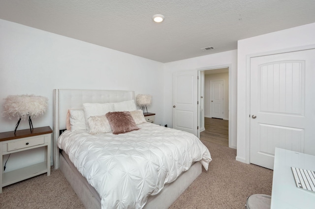 bedroom with a textured ceiling and light carpet