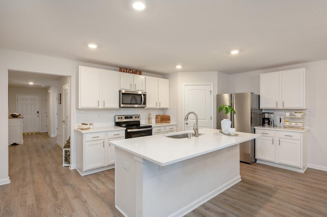 kitchen featuring light hardwood / wood-style floors, stainless steel appliances, white cabinets, sink, and a kitchen island with sink