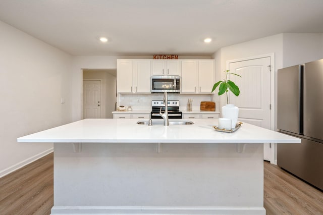 kitchen with light hardwood / wood-style flooring, appliances with stainless steel finishes, a large island, and white cabinets