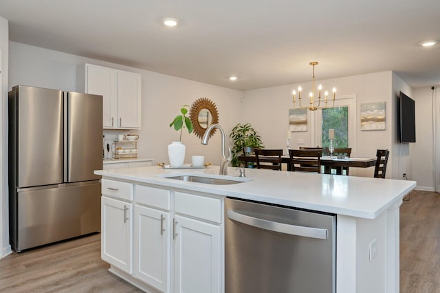 kitchen with stainless steel appliances, light hardwood / wood-style floors, white cabinetry, sink, and a kitchen island with sink