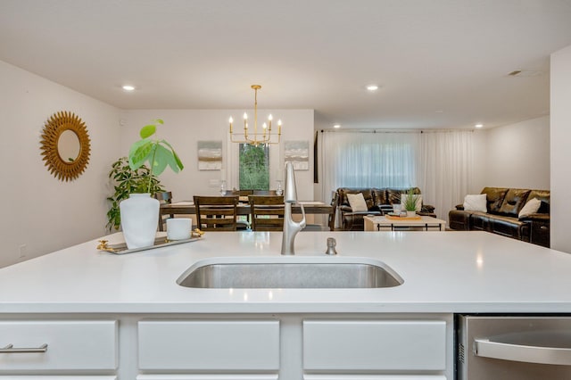 kitchen featuring an inviting chandelier, hanging light fixtures, sink, and a center island with sink