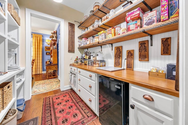 bar with wine cooler, hardwood / wood-style floors, white cabinetry, and butcher block counters
