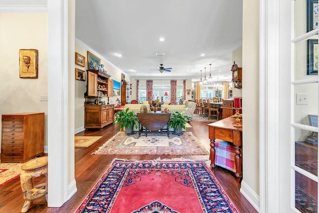 living room featuring ornamental molding, dark hardwood / wood-style flooring, and ceiling fan with notable chandelier
