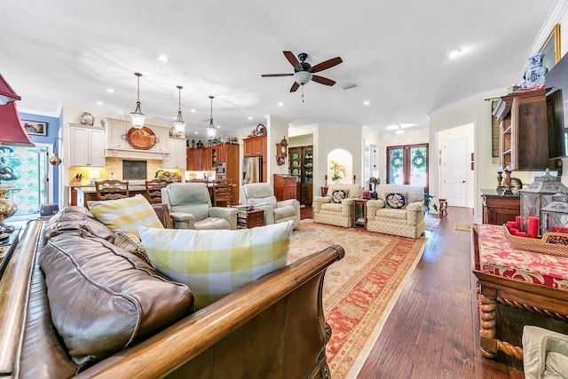 living room featuring ceiling fan, ornamental molding, and dark hardwood / wood-style floors