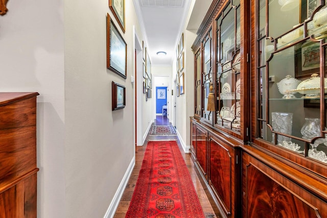 corridor with ornamental molding and dark wood-type flooring