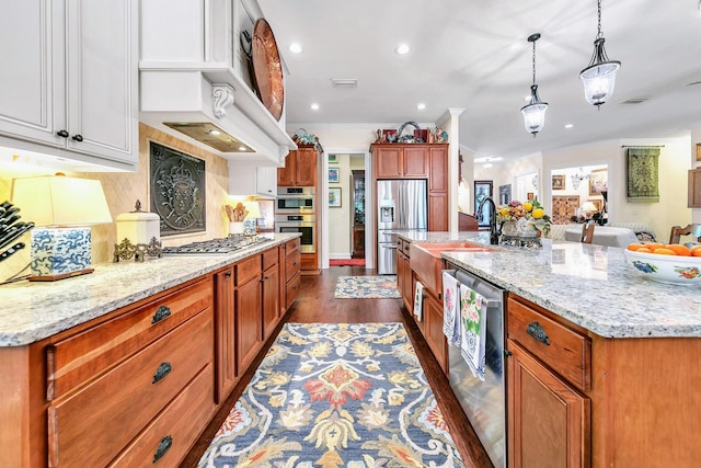 kitchen featuring a spacious island, white cabinets, stainless steel appliances, and hanging light fixtures