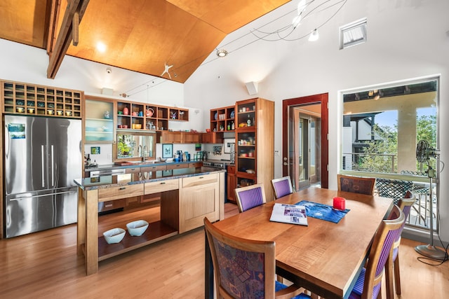 dining space with sink, light hardwood / wood-style flooring, and high vaulted ceiling