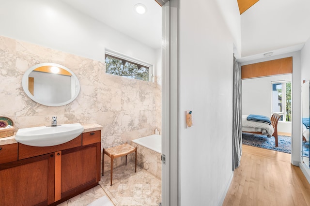 bathroom with vanity, hardwood / wood-style flooring, tile walls, and plenty of natural light