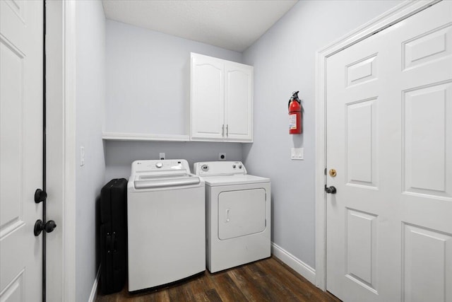 laundry area featuring dark wood-type flooring, washer and clothes dryer, a textured ceiling, and cabinets