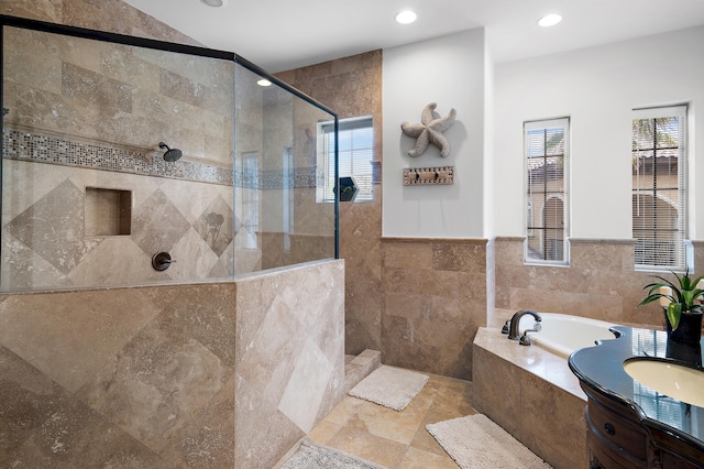 bathroom with tile walls, vanity, and plus walk in shower