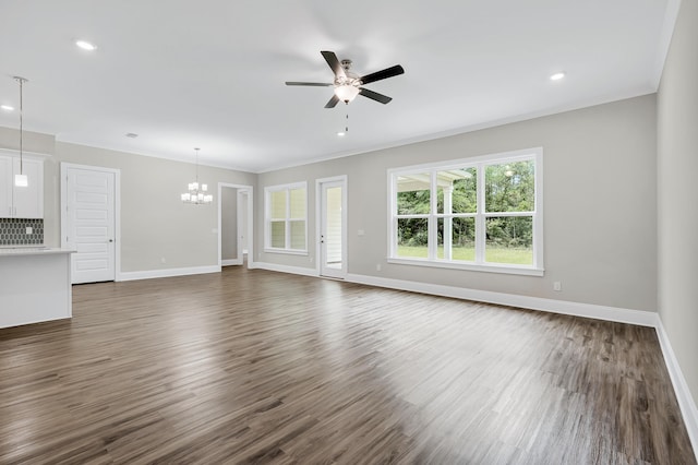 unfurnished living room with ceiling fan with notable chandelier, dark hardwood / wood-style flooring, and ornamental molding