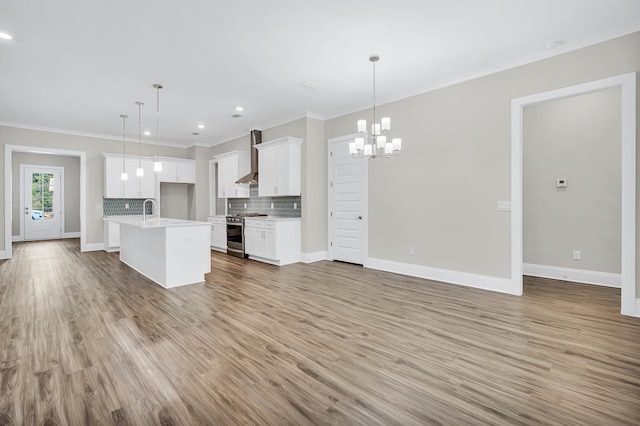 kitchen featuring white cabinets, an island with sink, decorative light fixtures, and stainless steel stove