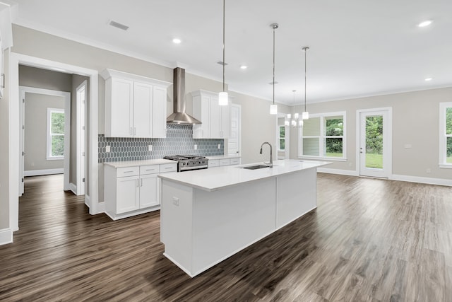 kitchen featuring sink, wall chimney exhaust hood, stainless steel range with gas cooktop, and white cabinetry