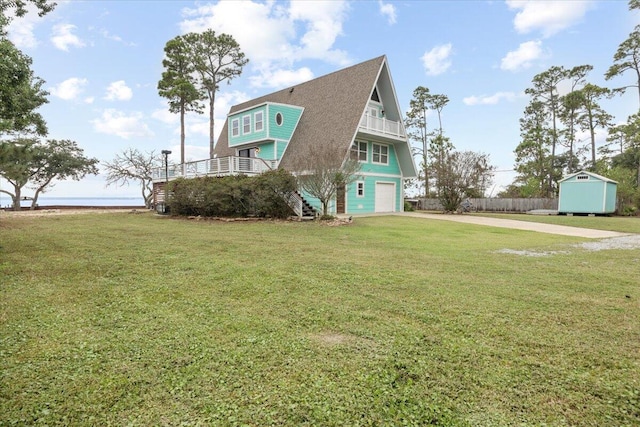 view of front of house featuring a garage, a front yard, a storage unit, and a balcony