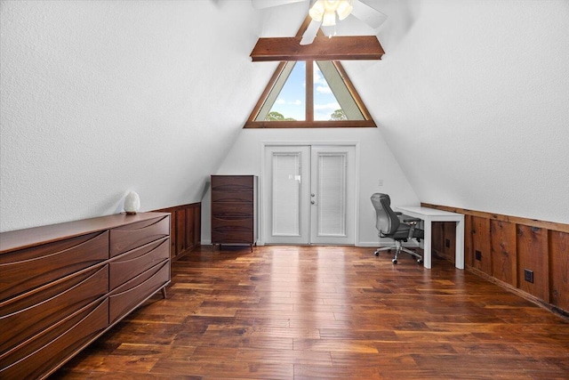 office space featuring dark hardwood / wood-style flooring, lofted ceiling, wooden walls, and ceiling fan